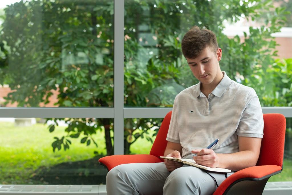 英国东北大学的学生道森·德科特坐在比德福德校园图书馆的椅子上写了一首诗